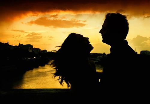 Силуэт мужчины и женщины на мосту реки